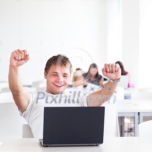 Portrait of a very happy young, male college student working on his laptop computer in a classroom/study room/library - expressing joy/success (shallow DOF; color toned image) Portrait of a very happy young, male college student working on his laptop computer in a classroom/study room/library - expressing joy/success (shallow DOF; color toned image)