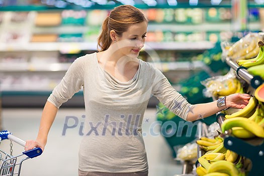 Beautiful youn woman shopping for fruits and vegetables in produce department of a grocery store/supermarket (shallow DOF; color toned image) Beautiful youn woman shopping for fruits and vegetables in produce department of a grocery store/supermarket (shallow DOF; color toned image)