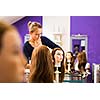 Pretty female hairdresser/haidressing apprentice/student training on an apprentice head