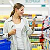 Beautiful young woman shopping in a grocery store/supermarket (color toned image)