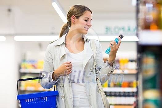 Beautiful young woman shopping in a grocery store/supermarket (color toned image)