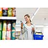 Beautiful young woman shopping in a grocery store/supermarket (color toned image)