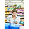 Beautiful young woman shopping in a grocery store/supermarket (color toned image)