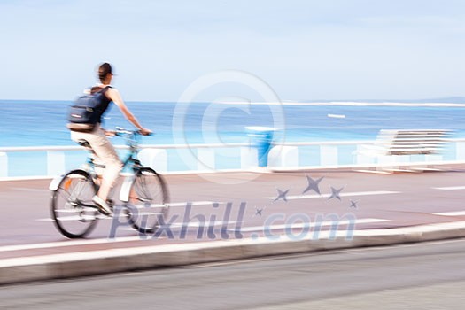 Great way to get around in a city -Motion blurred cyclist going fast on a city bike lane, by the sea shore Great way to get around in a city -Motion blurred cyclist going fast on a city bike lane, by the sea shore