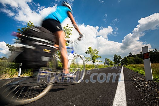 Female cyclist biking on a country road on a lovely sunny day (motion blurred image with copy space) Female cyclist biking on a country road on a lovely sunny day (motion blurred image with copy space)