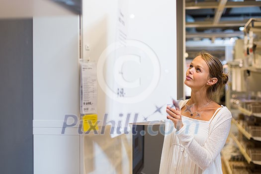 Pretty, young woman choosing the right furniture for her apartment in a modern home furnishings store (color toned image; shallow DOF) Pretty, young woman choosing the right furniture for her apartment in a modern home furnishings store (color toned image; shallow DOF)