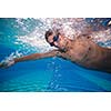 Young man swimming the front crawl in a pool - underwater shot (color toned image)