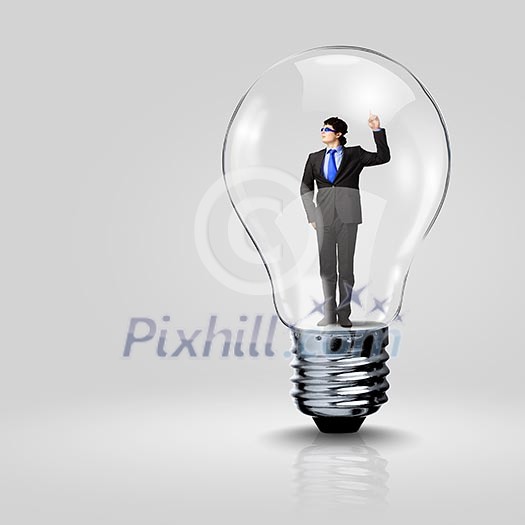 Image of young businessman in light bulb. New idea and inspiration Image of young businessman in light bulb. New idea and inspiration