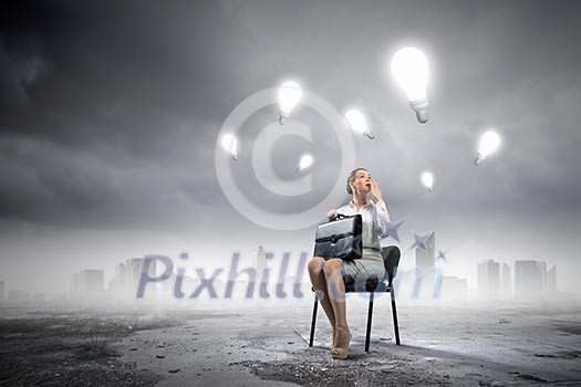 Image of businesswoman sitting on chair with suitcase in hands Image of businesswoman sitting on chair with suitcase in hands