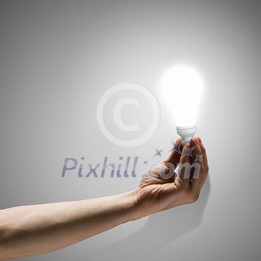 Close up image of human hand holding electrical bulb Close up image of human hand holding electrical bulb