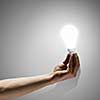 Close up image of human hand holding electrical bulb