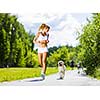 Young attractive sport girl running with dog in park
