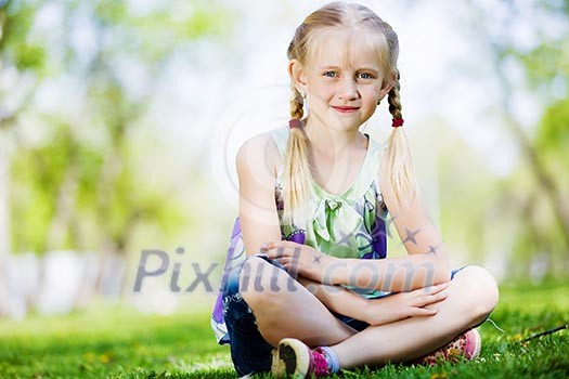 Image of little cute girl sitting on grass in park Image of little cute girl sitting on grass in park