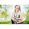 Image of little cute girl sitting on grass in park