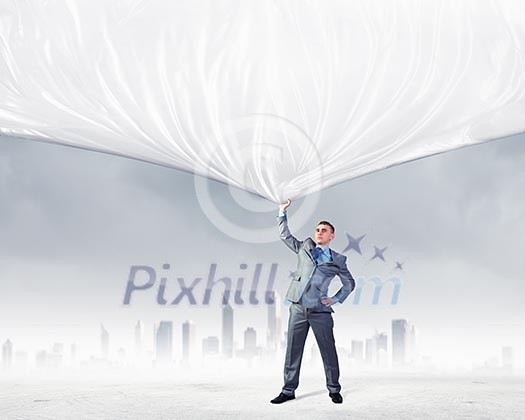 Image of young businessman pulling blank banner from above Image of young businessman pulling blank banner from above