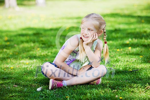 Image of little cute girl sitting on grass in park Image of little cute girl sitting on grass in park