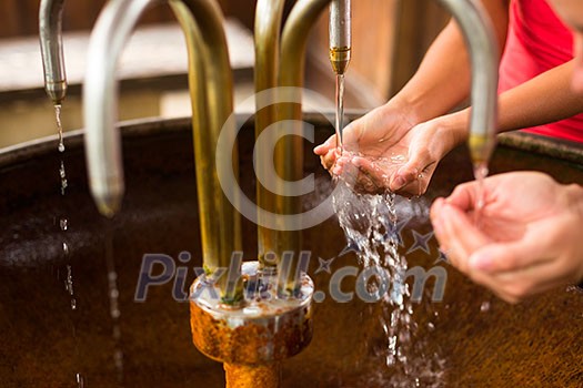 People filling up their hands with healthy mineral water from a wellspring in a spa (shallow DOF) People filling up their hands with healthy mineral water from a wellspring in a spa (shallow DOF)