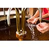 People filling up their hands with healthy mineral water from a wellspring in a spa (shallow DOF)