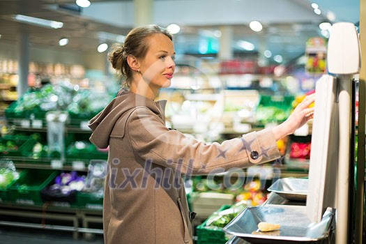 Beautiful young woman shopping for fruits and vegetables in produce department of a grocery store/supermarket Beautiful young woman shopping for fruits and vegetables in produce department of a grocery store/supermarket