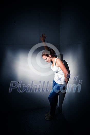 Young woman suffering from a severe depression, anxiety (very harsh lighting is used on this shot to underline/convey the gloomy mood of the scene) Young woman suffering from a severe depression, anxiety (very harsh lighting is used on this shot to underline/convey the gloomy mood of the scene)