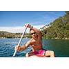 Handsome young man on a canoe on a lake, paddling, enjoying a lovely summer day