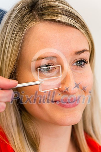 Optometry concept - pretty young woman having her eyes examined by an eye doctor (color toned image; shallow DOF) Optometry concept - pretty young woman having her eyes examined by an eye doctor (color toned image; shallow DOF)