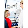 Optometry concept - pretty young woman having her eyes examined by an eye doctor (color toned image; shallow DOF)