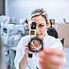 Optometry concept - pretty young optometrist at work, examinating your eyes (color toned image; shallow DOF)
