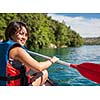 Pretty, young woman on a canoe on a lake, paddling, enjoying a lovely summer day