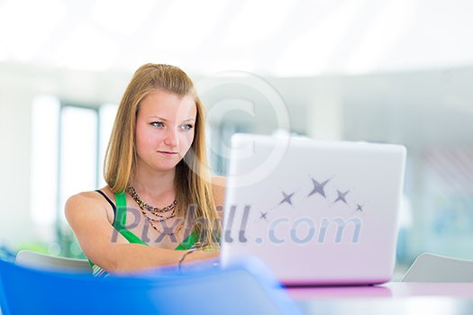 pretty female college student working on her laptop computer on campus, before class (color toned image; shallow DOF) pretty female college student working on her laptop computer on campus, before class (color toned image; shallow DOF)
