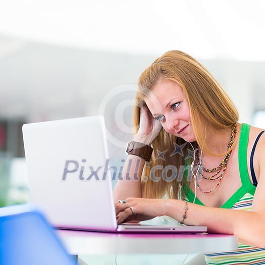 pretty female college student working on her laptop computer on campus, before class (color toned image; shallow DOF) pretty female college student working on her laptop computer on campus, before class (color toned image; shallow DOF)