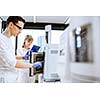 Two young researchers carrying out experiments in a lab (shallow DOF; color toned image)