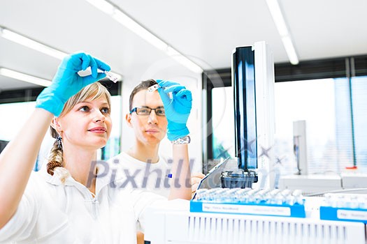 Two young researchers carrying out experiments in a lab (shallow DOF; color toned image) Two young researchers carrying out experiments in a lab (shallow DOF; color toned image)