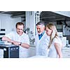 Team of researchers carrying out experiments in a lab (shallow DOF; color toned image)