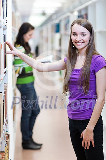In the library - pretty, female student searching for books in a high school/university library (color toned image) In the library - pretty, female student searching for books in a high school/university library (color toned image)