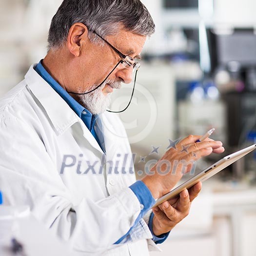 Senior doctor/scientist using his tablet computer at work (color toned image) Senior doctor/scientist using his tablet computer at work (color toned image)