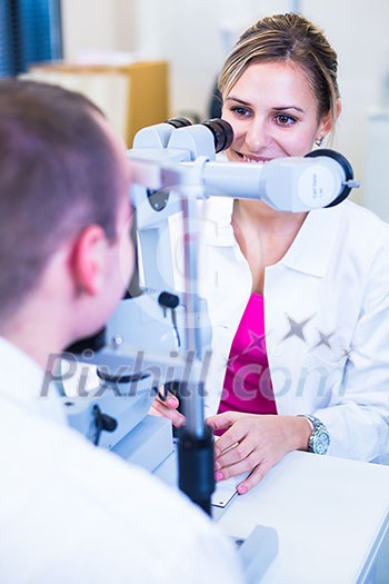 Optometry concept - handsome young man having his eyes examined by an eye doctor (color toned image; shallow DOF) Optometry concept - handsome young man having his eyes examined by an eye doctor (color toned image; shallow DOF)
