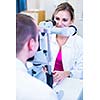 Optometry concept - handsome young man having his eyes examined by an eye doctor (color toned image; shallow DOF)