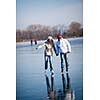 Couple ice skating outdoors on a pond on a lovely sunny winter day