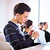 young, handsome male college student sitting in a classroom full of students during class (color toned image; shallow DOF)