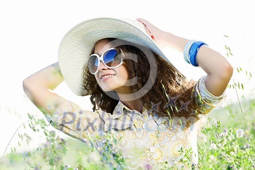 Young beautiful girl in hat and glasses sitting in grass Young beautiful girl in hat and glasses sitting in grass