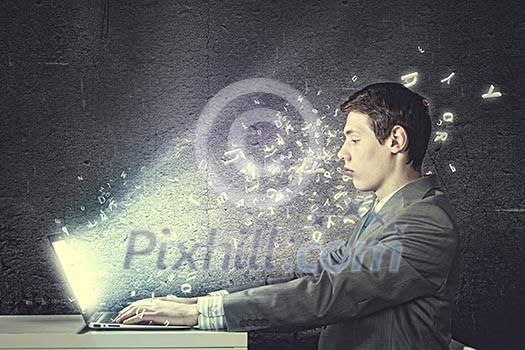 Thoughtful young man in suit seriously looking in laptop Thoughtful young man in suit seriously looking in laptop