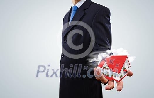 Close up of businessman holding house model in palm Close up of businessman holding house model in palm