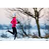 Young woman running outdoors on a cold winter day (motion blurred image)