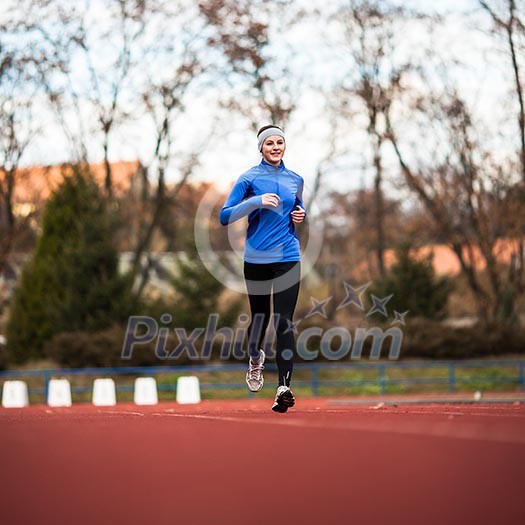 Young woman running at a track and field stadium Young woman running at a track and field stadium