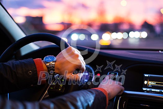 Driving a car at night -man driving his modern car at night in a city (shallow DOF; color toned image) Driving a car at night -man driving his modern car at night in a city (shallow DOF; color toned image)