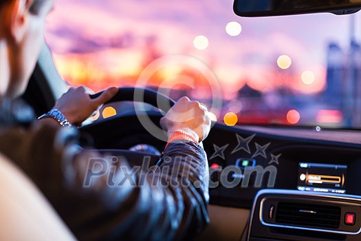 Driving a car at night -man driving his modern car at night in a city (shallow DOF; color toned image)