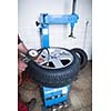 Auto mechanic in a garage checking the air pressure in a tyre with a pressure gauge  (shallow DOF; color toned image)