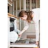 Housework: young woman putting dishes in the dishwasher