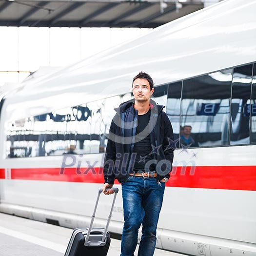 Just arrived: handsome young man walking along a platform at a modern train station Just arrived: handsome young man walking along a platform at a modern train station